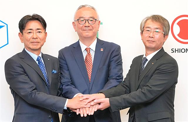 手を取り合うＪＴの嶋吉副社長（左）、塩野義製薬の手代木会長兼社長ＣＥＯ（中央）、鳥居薬品の近藤社長（右）